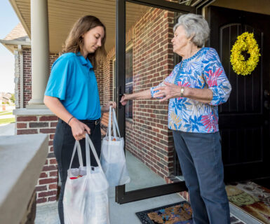 Young woman delivering groceries to the Illinois house of an older woman.
